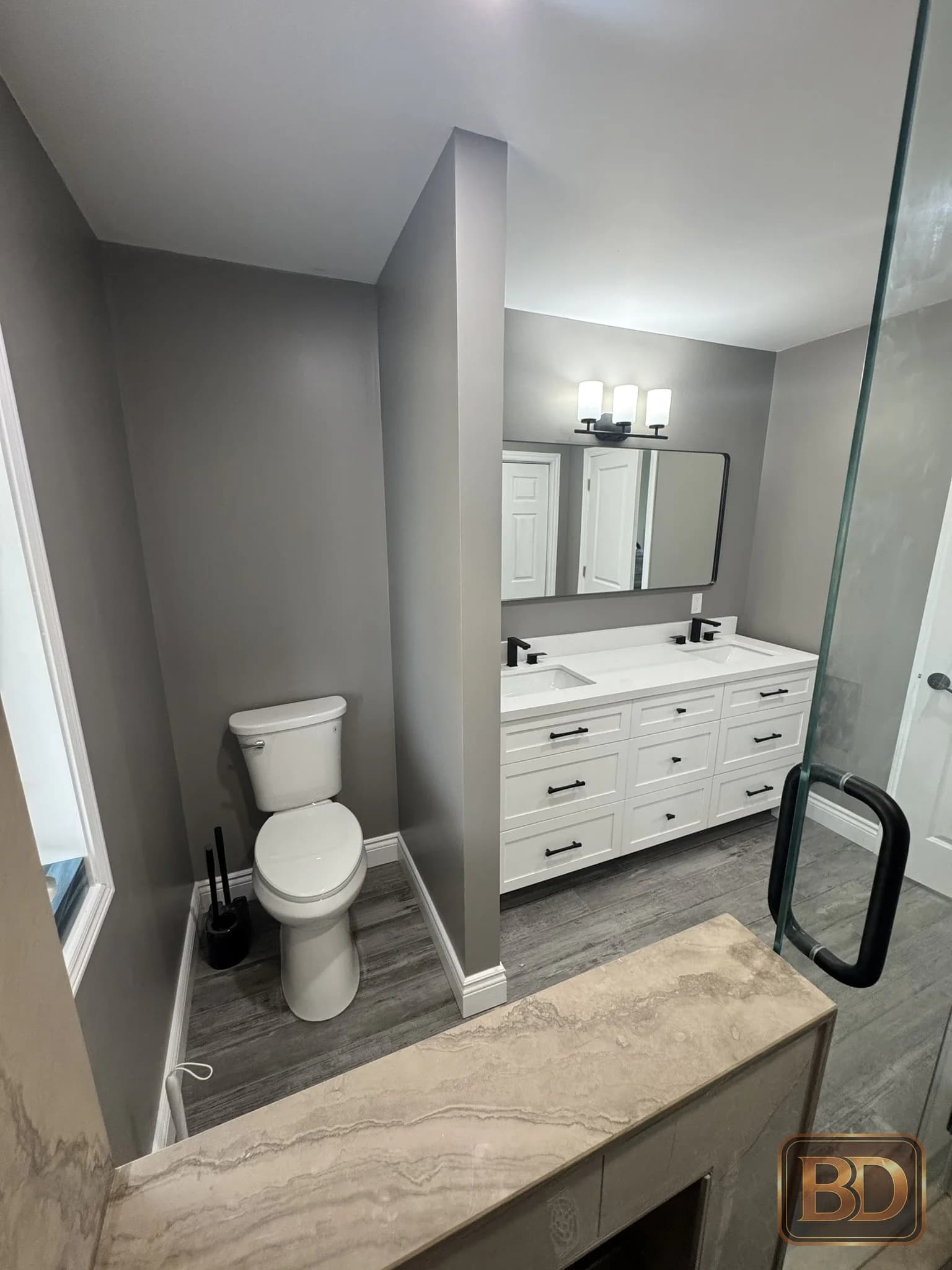 Completed bathroom with a double vanity, toilet, and glass shower