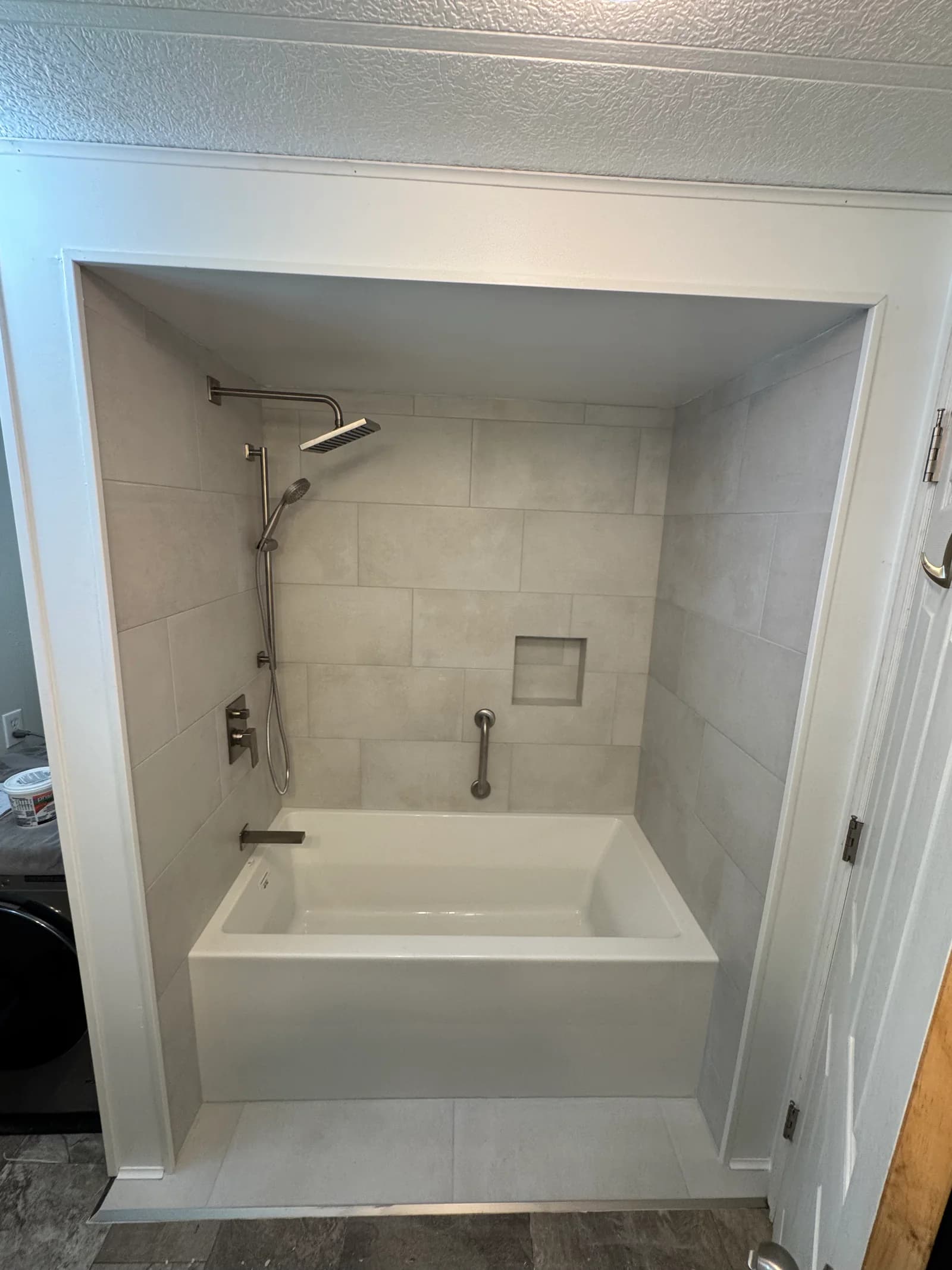 Completed tiled tub and shower with rain shower and wall niche