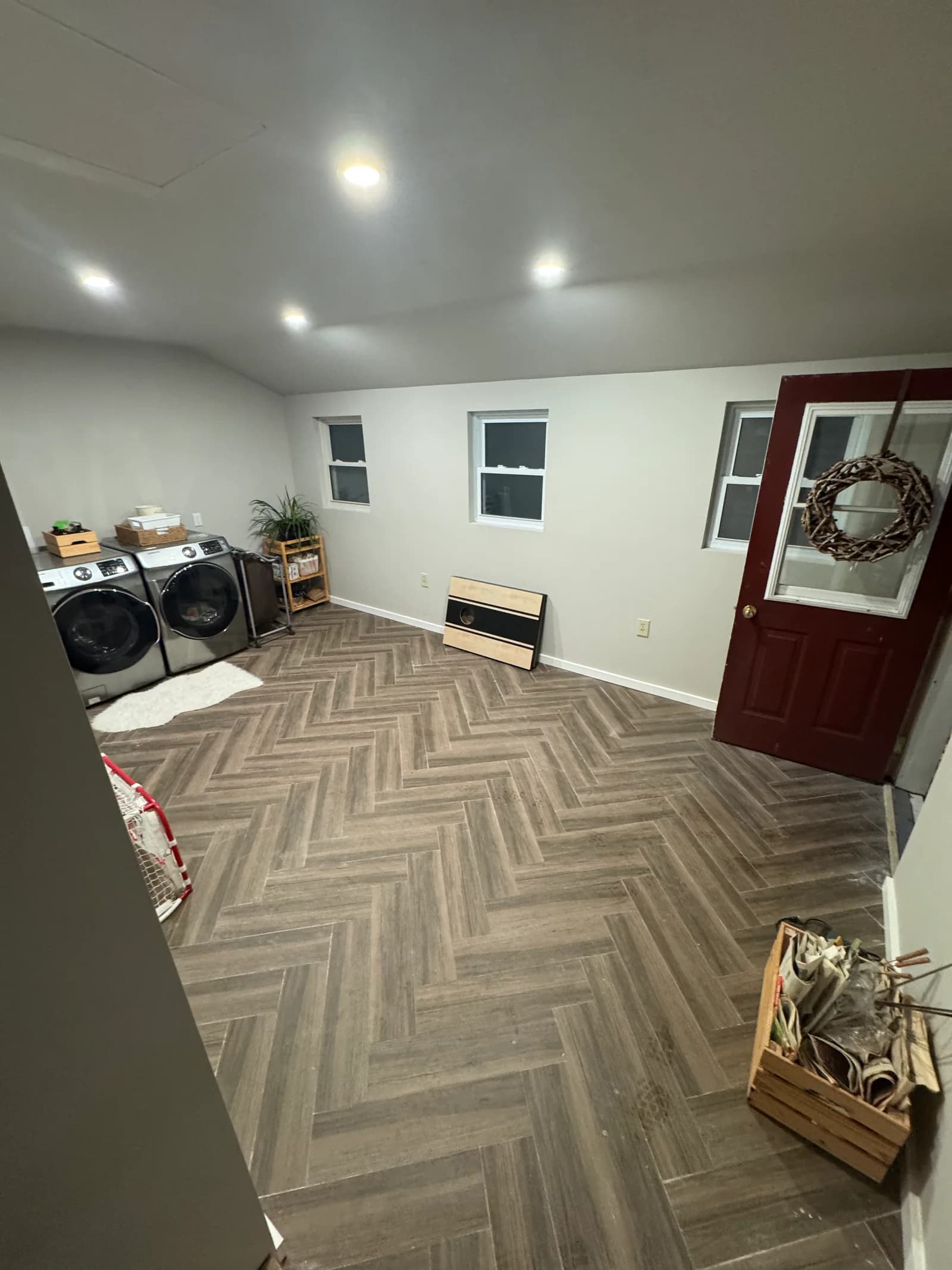 Renovated laundry room with herringbone-pattern flooring and recessed lighting