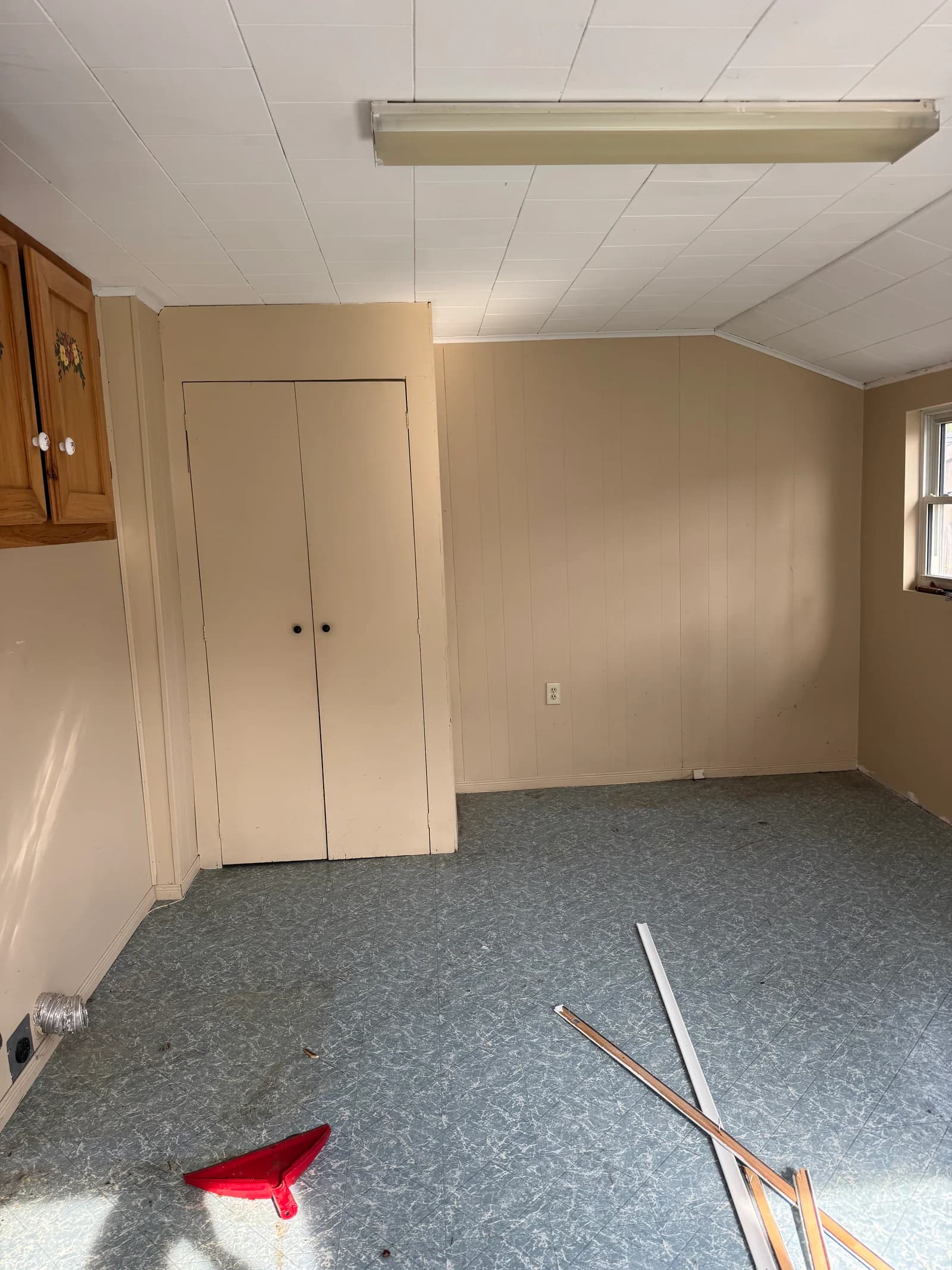 Laundry room before renovation with paneled walls and old flooring